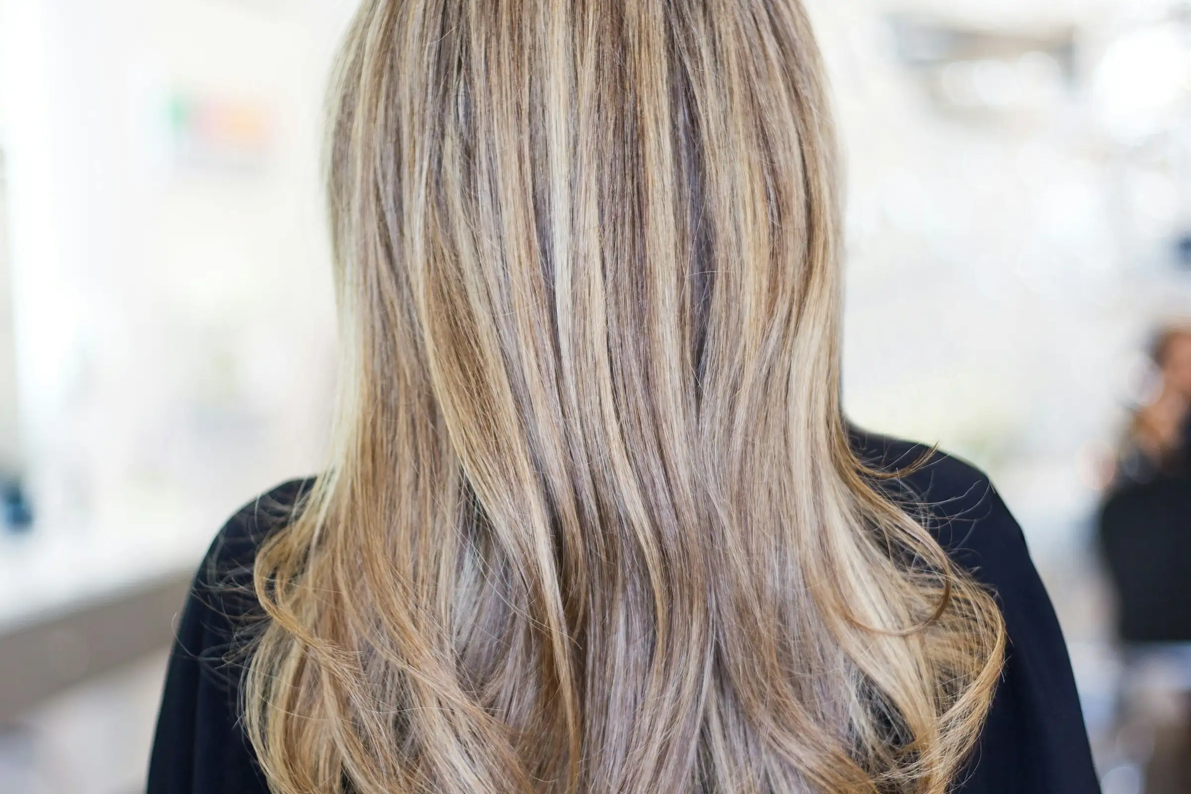 Long, smooth blonde hair from behind, in a bright salon